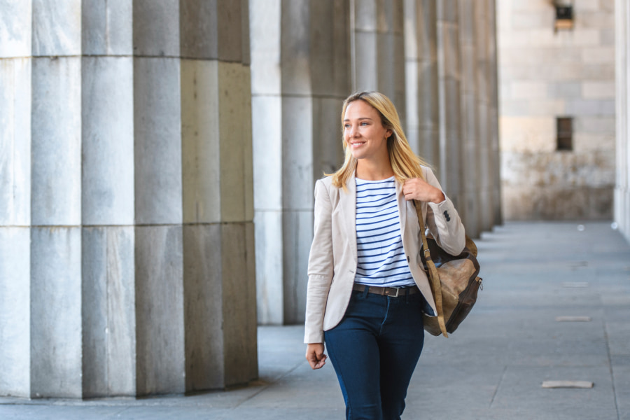 Woman walking with bag next to tall pillars